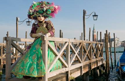 A woman in a green Mardi Gras dress and mask in Venice