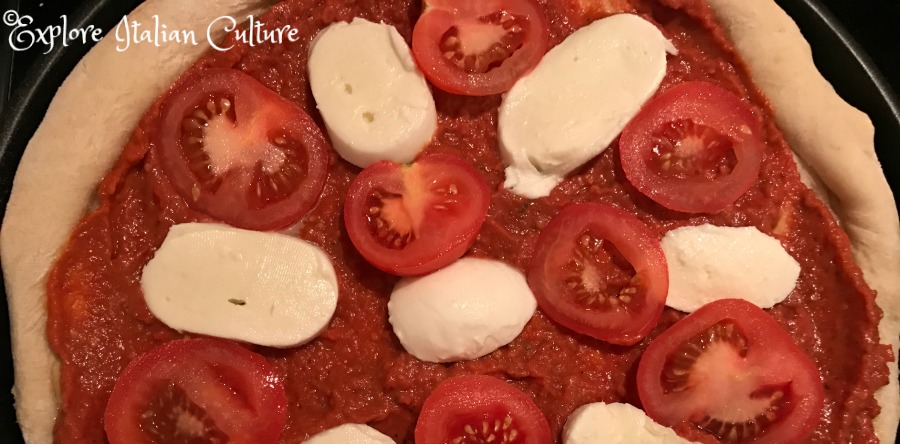 Mozzarella slices and sliced tomatoes on a pizza Margherita.