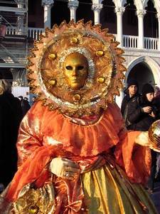 A woman dressed in an orange costume and mask for Mardi Gras in Venice